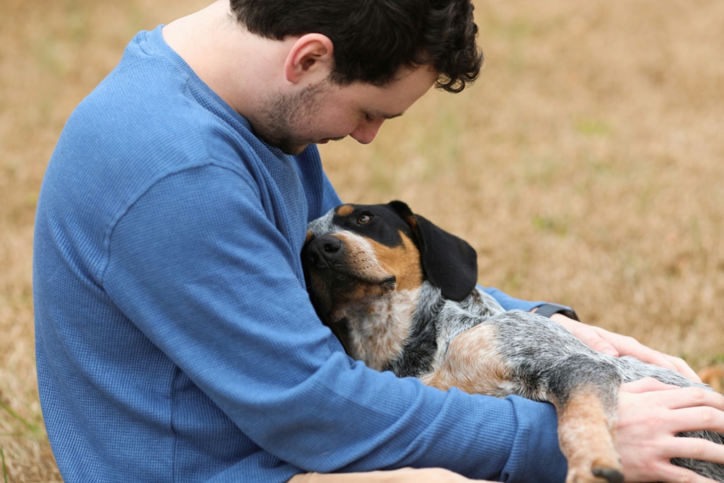 Chien heureux dans les bras de son maître après détection et soins des problèmes bucco-dentaires grâce à Oven-Baked Tradition